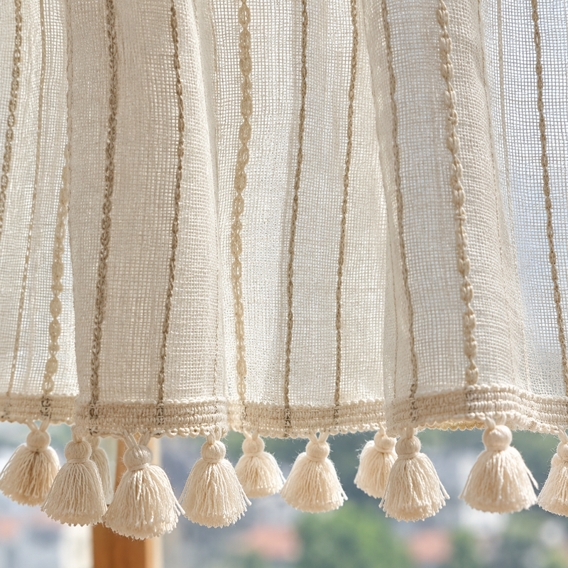 Brise-bise beige à rayures brodées, base tulle et pompons – détail de la matière