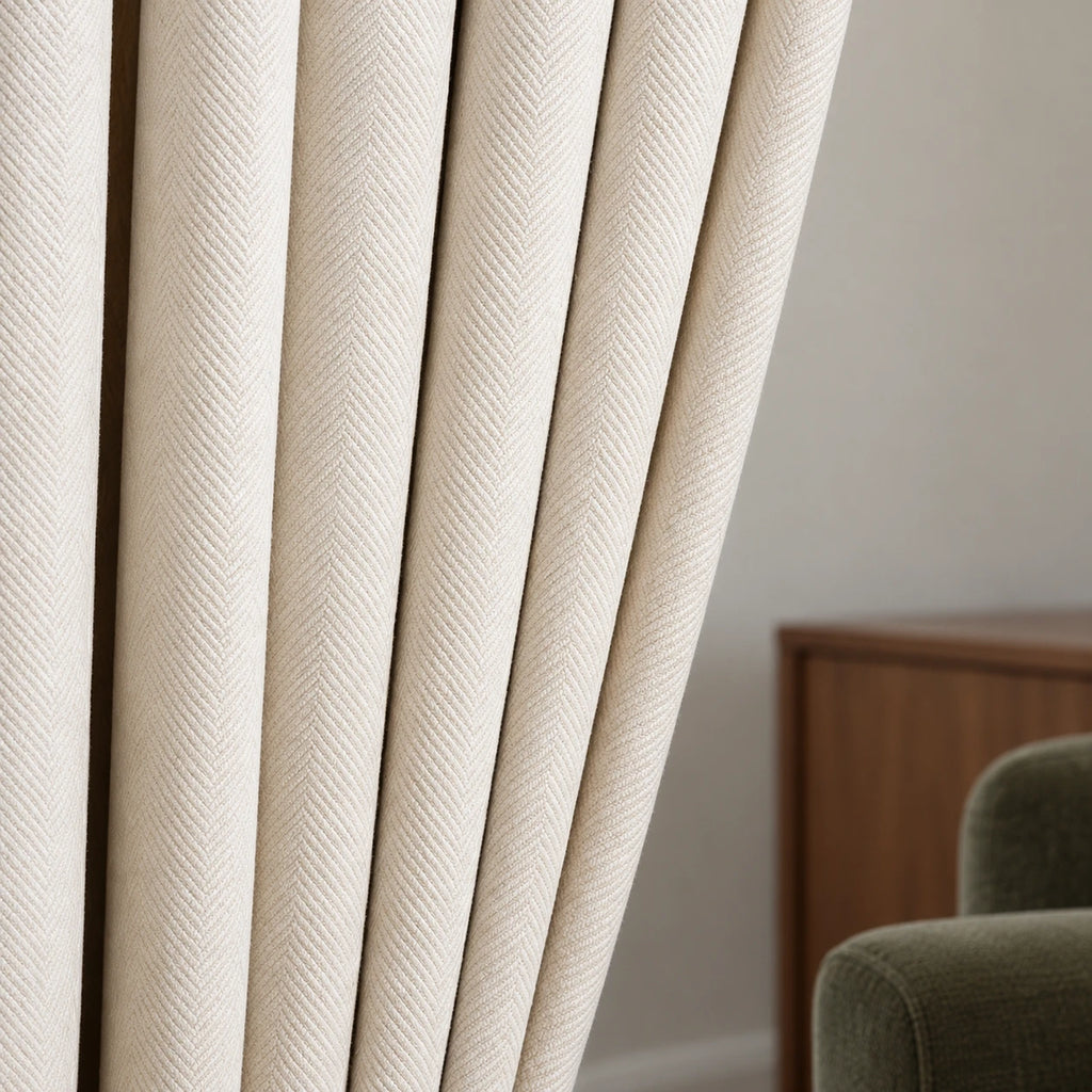Détail du tissage à chevrons du rideau en chenille blanc cassé, avec un salon en arrière-plan.