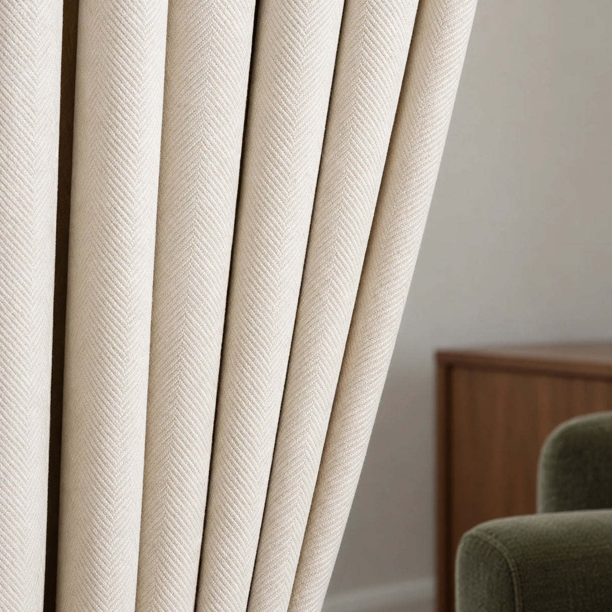 Détail du tissage à chevrons du rideau en chenille blanc cassé, avec un salon en arrière-plan.
