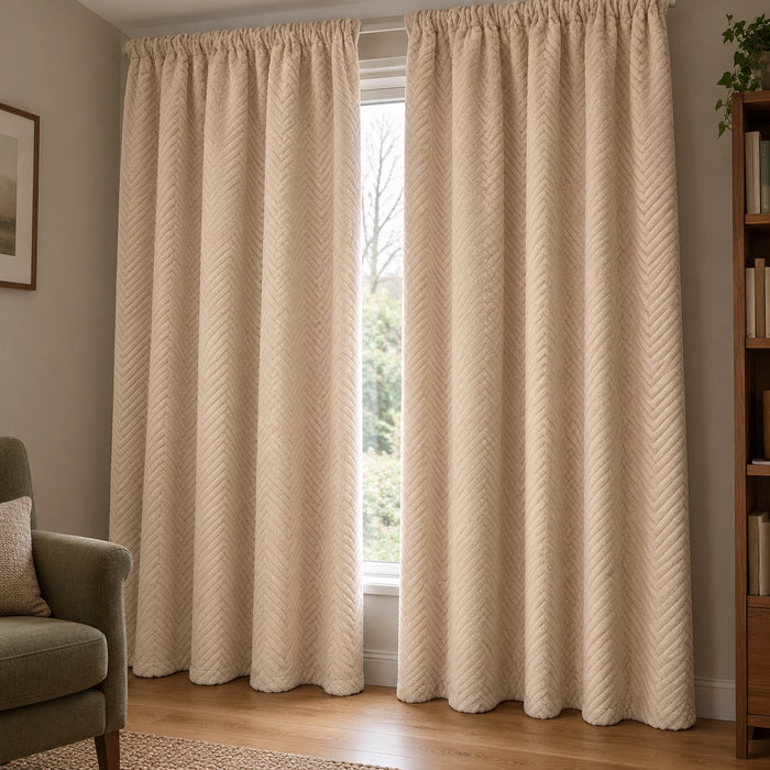 Rideau thermique polaire beige à chevrons et tête froncée, dans un coin lecture éclairé par une fenêtre.
